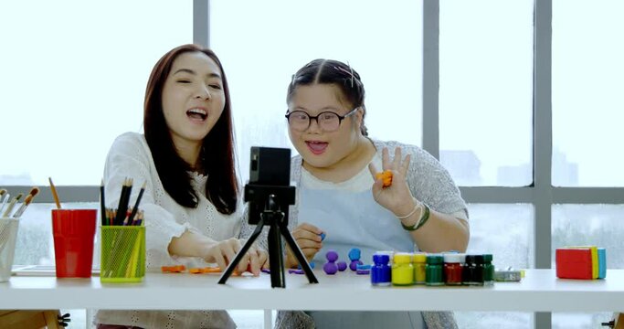 Asian mother and Autistic daughter learning to practice Plasticine and painting Study online via smartphone at home with intention happy. Girl enjoy doing art activities to enhance imagination skill