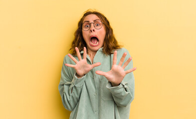 young pretty woman feeling terrified, backing off and screaming in horror and panic, reacting to a...