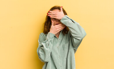 young pretty woman covering face with both hands saying no to the camera! refusing pictures or...
