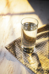 Glass of water on wooden table, sunny morning