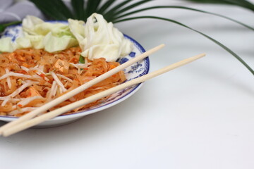 Thai food Pad Thai (national dish) served in a Chinese-style patterned bowl. Place it on a white table.