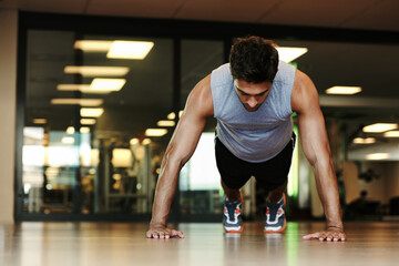 Fototapeta na wymiar Pushing himself to new limits. A handsome man wearing sports clothing doing pushups in the gym.