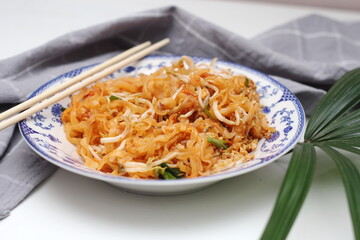 Thai food Pad Thai (national dish) served in a Chinese-style patterned bowl. Place it on a white table.