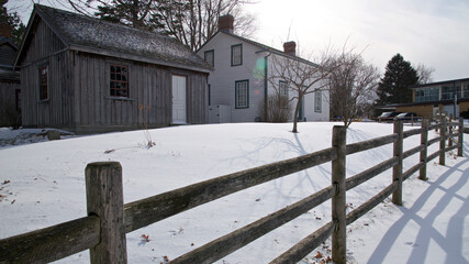 Colonial-style house exterior with wooden post and rail fence in winter.