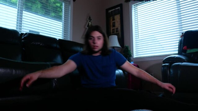 Man sits at home and stretches with his legs out wide in a straddle position, post work out stretch concept