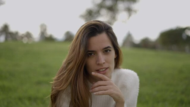 Young dark-haired woman makes shushing gesture, close frontal view