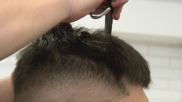 Close up view: Asian male's black hair is texturized using a hair clip