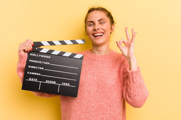 young pretty woman feeling happy, showing approval with okay gesture. cinema clapper concept