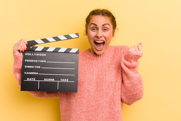 young pretty woman feeling shocked,laughing and celebrating success. cinema clapper concept