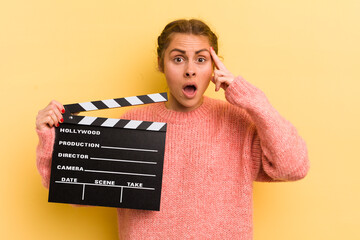 young pretty woman looking surprised, realizing a new thought, idea or concept. cinema clapper...