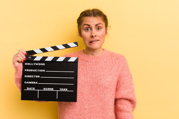 young pretty woman looking puzzled and confused. cinema clapper concept