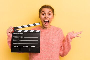 young pretty woman feeling happy, surprised realizing a solution or idea. cinema clapper concept