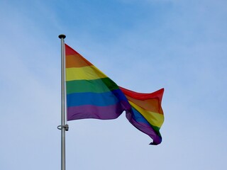 Rainbow pride flag waving in strong wind on a cloudy day. Symbol of LGBT community