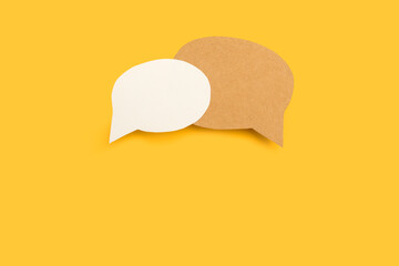 Dos burbujas de chat sobre un fondo amarillo liso y aislado. Vista superior y de cerca. Copy space. Concepto: símbolo de las conversaciones y los diálogos.  - obrazy, fototapety, plakaty
