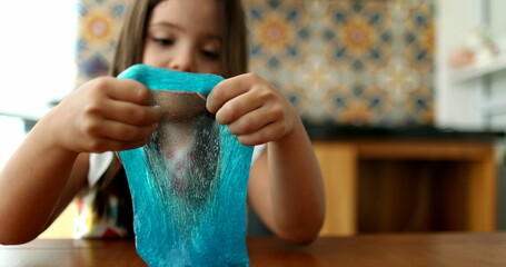 Child hands playing with slime goo. Little girl close-up hand and fingers with sticky elastic plasticine