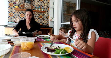 Casual family eating lunch at home together. Sisters with children gathered together, real life candid