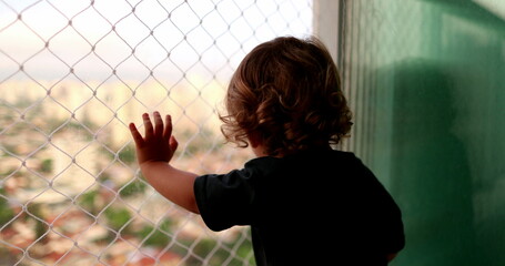 Baby child hand leaning on window balcony with safety net