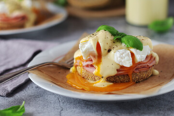 Egg benedict sandwiches - muffin with poached egg, ham and hollandaise sauce