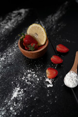 fresh natural red strawberries on a black background with lemon slice, source of vitamin C