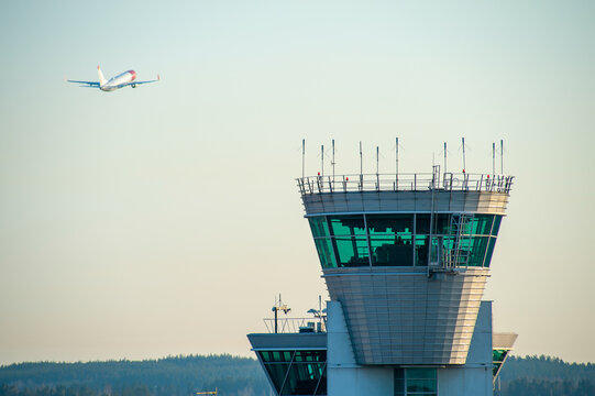 Air traffic control tower of Helsinki-Vantaa airport with a departing Norwegian Air Shuttle Boeing 737 in the background.