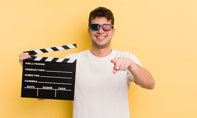 young handsome man pointing at camera choosing you. cinema clapper concept