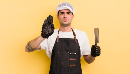 young handsome man looking serious showing open palm making stop gesture. butcher concept