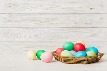 Multi colors Easter eggs in the woven basket on colored background . Pastel color Easter eggs. holiday concept with copy space