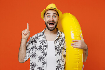 Young tourist man wear beach shirt hat hold inflatable ring holding index finger up with great new...