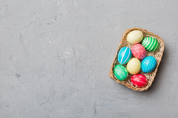 Multi colors Easter eggs in the woven basket on colored background . Pastel color Easter eggs. holiday concept with copy space