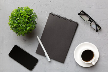 Modern office desk table with notebook, smartphone and other supplies with cup of coffee. Blank notebook page for you design. Top view, flat lay