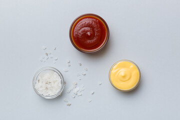 Bowl of salt, ketchup and cheese sauce on colored background, top view with copy space