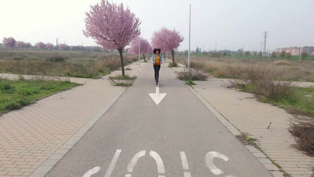 Video of young afro woman looking away while riding electric push scooter on road at the city.