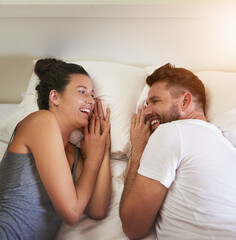 Its always laughter and happiness when it comes to her. Cropped shot of a young attractive couple lying in bed together at home.