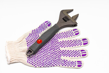 a metal adjustable wrench next to which lies a work glove