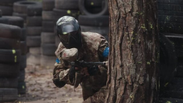 High-quality. Paintball sport player wears protective mask aiming gun. Shot from a paintball gun. Portrait of cheerful adult people playing war on the battlefield.
