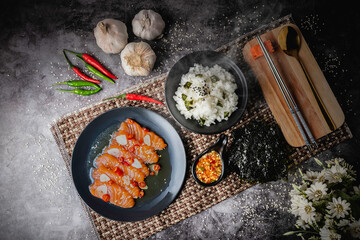Salmon in fish sauce, Japanese style food, popular with Thai people nowadays. Red meat on a black plate