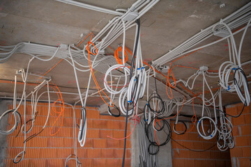 interior of skyscraper floor under construction. Cables, pipes and tubes hanging from ceiling of...