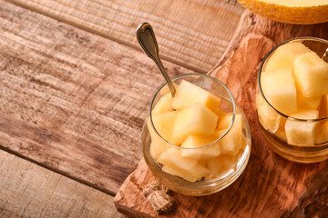Melon. Pieces of fresh melon for making fruit dessert in glass on an old wooden background. Mock up. Top view.