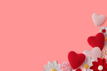 Composition of handmade crochet and wool flowers and hearts with copy space on pink background....