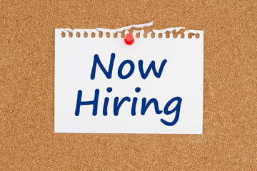 Now hiring note message on paper on a bulletin board