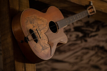 Vintage guitar hanging on the old wooden wall. Close up.