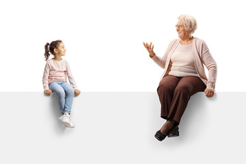 Elderly woman sitting on a blank panel and talking to a little girl