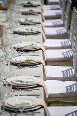 Fototapeta premium Gorgeous vintage wedding table setting. Banquet. The chairs and table for guests, served with cutlery, flowers and crockery, covered with a tablecloth.