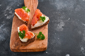 Mini sandwiches with salmon, curd cheese, parsley and rye bread in form of hearts. Valentine's day homemade creative food. Love breakfast design. Selective focus and copy space