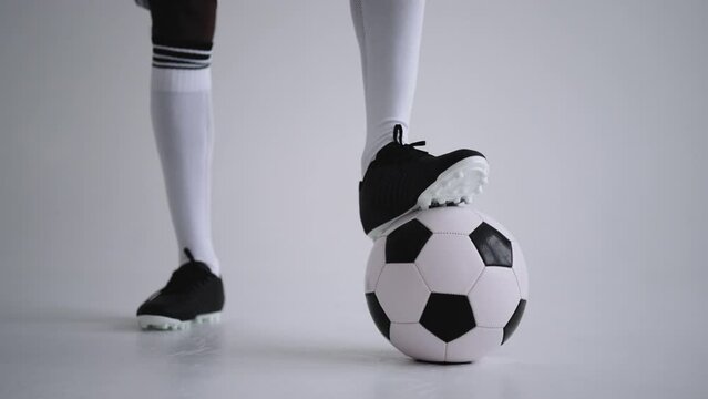 football ball and legs of football in boots and knee socks in studio, closeup view