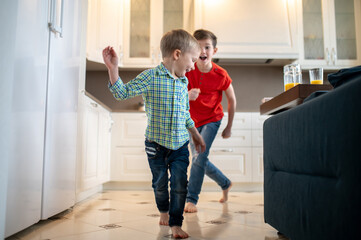 Mischievous Caucasian boy chasing his sibling indoors