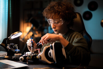 Close-up soldering, young teenager fixes cables,robot wires, small smoke rises from heated...