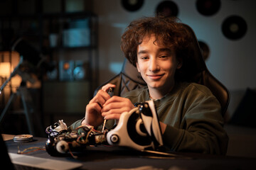 A young boy passionate about electronics, gifted with manual skills, twists his own robot model,...