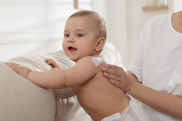 Mother applying body cream on her little baby at home, closeup