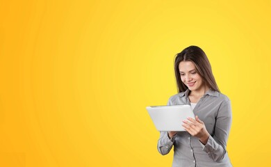 Young female student with tablet posing on background